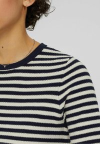 Randig stickad tröja i marinblått och krämfärgat, med en strukturerad tyg, ribbad halsringning och en figurnära passform. Enkelt mönster med horisontella ränder.