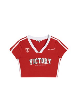 Camiseta corta roja con cuello en V blanco, mangas cortas y franjas laterales. Presenta un estampado de "VICTORY" y una insignia en el pecho.