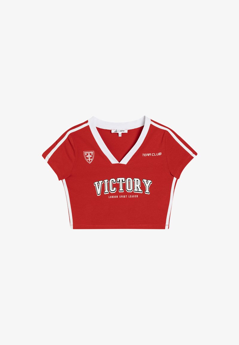 Camiseta corta roja con cuello en V blanco, mangas cortas y franjas laterales. Presenta un estampado de "VICTORY" y una insignia en el pecho.