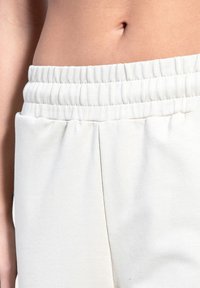 Lyse elastiske shorts med glat tekstur og sidelommer, med en afslappet pasform og minimale syningsdetaljer.