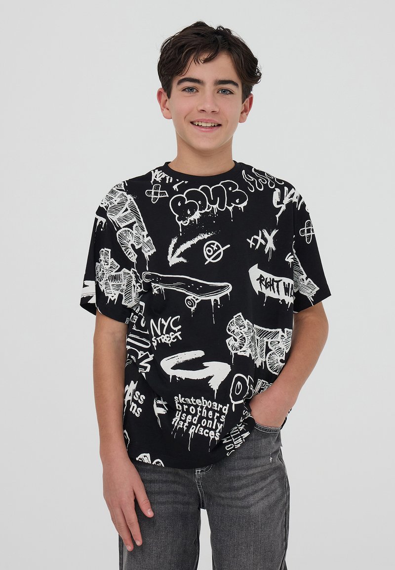 T-shirt nera a maniche corte con testo e illustrazioni in stile graffiti bianco, colletto rotondo, vestibilità rilassata e texture spessa in evidenza.