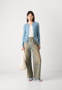 Light blue cable-knit cardigan, white top, high-waisted faded denim pants, light blue heeled sandals, and a cream tote bag.