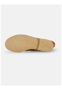 Sole di una scarpa con una base in gomma beige texturizzata, caratterizzata da una parte superiore in pelle marrone liscia con una lucentezza sottile e dettagli minimi.