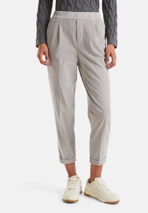 Pantalones de pana gris claro con un corte relajado, que presentan pliegues, bolsillos laterales y puños enrollados, combinados con zapatillas blancas.