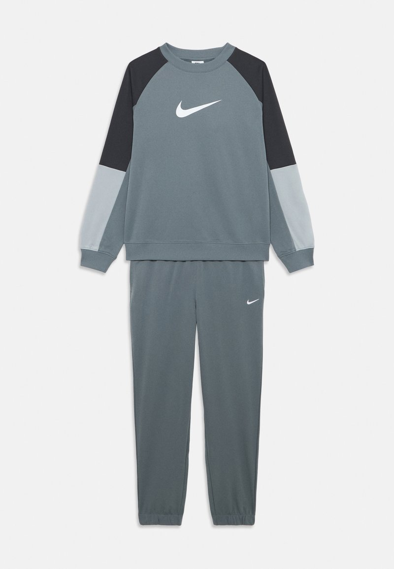 Pelēks Nike sporta tērps ar garām piedurknēm krāsu blokā piegrieztu džemperi un atbilstošām sporta biksēm, abiem ar baltu Nike swoosh logo.