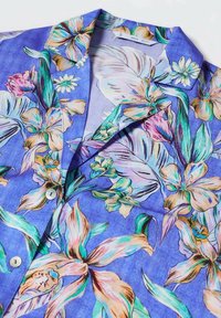 Camicia a maniche corte floreale in tonalità di blu, con grandi fiori tropicali colorati e foglie verdi su un tessuto testurizzato. Chiusura a bottoni.