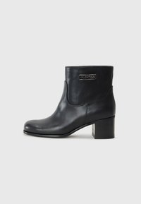 Černá kožená kotníčková bota s kulatou špičkou, mírným blokovým podpatkem a zlatým logem na boku. Hladká textura s minimalistickým designem.