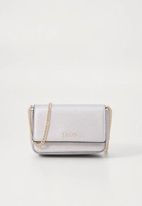 Sac bandoulière argenté avec une finition texturée, une bandoulière chaîne dorée et un logo embossé. Il présente un rabat et une forme rectangulaire compacte.