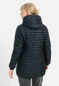 Mørkeblå pufferjakke med hætte, med et quiltet design og elastiske manchetter. Bagsiden viser en lige kant og en glat overflade.