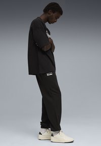 Sort oversized t-shirt, sorte sweats med "Turbo" logo, og hvide sneakers med sorte accenter. Glatte teksturer, afslappet pasform.