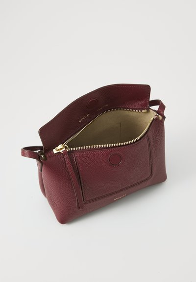 Bolsa de mão em pele borgonha com um acabamento texturizado, apresentando um fecho com zíper e um bolso exterior. O interior é bege com ferragens em tom dourado.