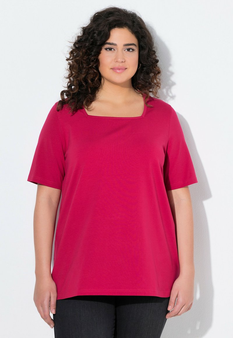T-shirt fuchsia avec un col carré, des manches courtes et une coupe ample. Fabriqué en tissu doux avec une texture lisse. Porté avec un pantalon noir.