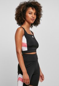 Czarny crop top z różowymi i białymi akcentami, wykonany z elastycznego materiału. Stylizowany z dopasowanymi szortami o wysokim stanie.
