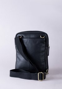 Black leather bag with a textured surface, rectangular shape, adjustable strap, and gold-tone hardware accents. Minimalist design, no visible embellishments.