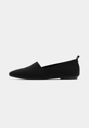 Chaussure noire plate avec un bout pointu, finition en tissu doux, design minimaliste, petit talon et une petite languette à l'arrière pour un enfilage facile.