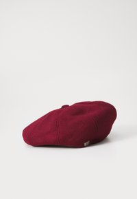 Burgundy wool beret with rounded shape, flat top, and stitched detailing. Features a small metallic logo on the side.