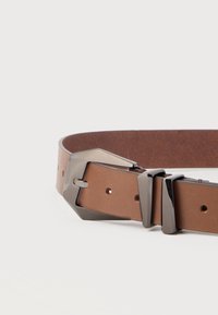 Cintura in pelle marrone con fibbia geometrica argentata lucida e due passanti abbinati su sfondo bianco neutro.