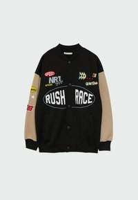 Veste universitaire noire et beige avec fermeture à boutons, texte "RUSH RACE", écussons de course et manches décorées.
