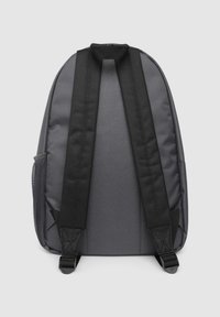 Szary materiałowy plecak z czarnymi wyściełanymi paskami, teksturowaną siateczkową boczną kieszenią oraz uchwytem do noszenia na górze. Prosty design, bez widocznych znaków towarowych.