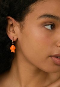 Guldørering med en orange gummibjørn charme. Charmer har teksturerede detaljer og et legesyg, skulpturelt design.