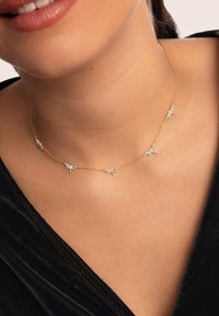 Collar de cadena de oro con pequeños charms de libélulas azules espaciados uniformemente a lo largo de su longitud. Los detalles del colgante añaden textura y diseño.
