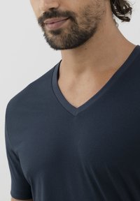 Námořnické tričko s výstřihem do V vyrobené z hladkého materiálu, s krátkými rukávy a přiléhavým střihem. Minimalistický design bez viditelných vzorů.