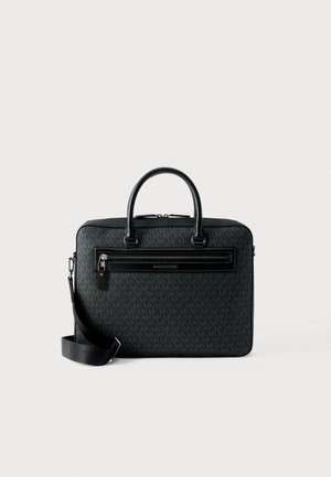 Geantă tip servietă neagră Michael Kors cu model monogramă, mânere duble, buzunar frontal cu fermoar și curea de umăr ajustabilă pe fundal alb.