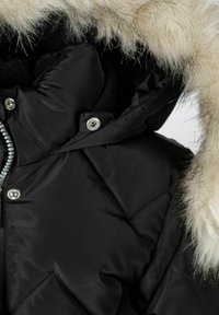 Chaqueta de plumas negra con un diseño acolchado, con capucha con borde de piel, botones a presión plateados y cremallera en la parte delantera. Textura suave.