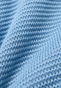 Hellblauer Strickstoff mit einer strukturierten Oberfläche, der ein regelmäßiges Muster aus erhabenen Maschen aufweist, das einen subtilen Rippeneffekt erzeugt.