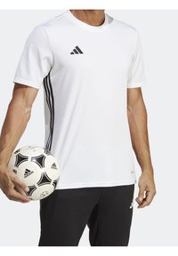 Bílý sportovní trik Adidas s krátkým rukávem, síťovina na ramenou, tři černé pruhy po stranách, doplněné černými kalhotami a fotbalovým míčem.