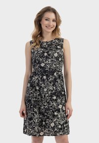 Ärmelloses schwarzes Kleid mit weißem Blumenmuster, enganliegendem Oberteil, ausgestelltem Rock; glatter Stoff, knielange Länge, runder Ausschnitt, minimale Details.