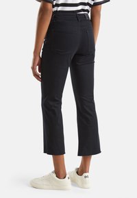 Svarta högmidjade korta byxor med bakfickor och en elegant design, kombinerade med vita sneakers.