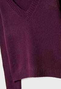 Pull en V de couleur prune, avec un col, des poignets et un ourlet côtelés, présentant un tissu tricoté texturé et une coupe décontractée.