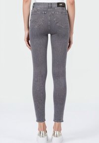 Grijze denim skinny jeans met een hoge taille, vijf zakken en een rafelszoom. De stof heeft een subtiele textuur en minimale vervaging.