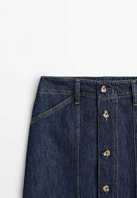 Jupe en jean bleu foncé avec fermeture boutonnée verticale à l'avant et coutures visibles à la taille et sur les poches latérales.