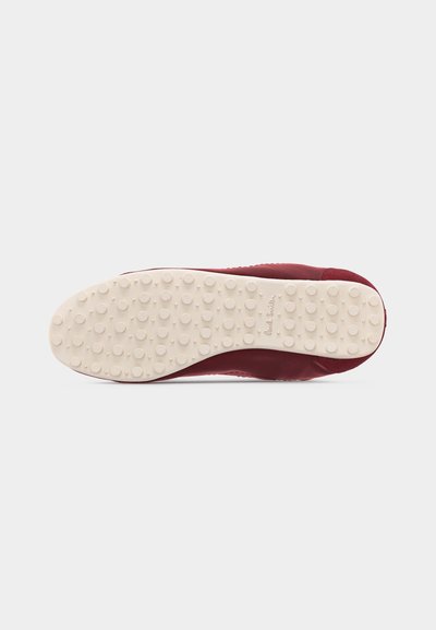 Εσωτερική σόλα μπορντό παπουτσιού με μπεζ εξωτερική σόλα από καουτσούκ, που διαθέτει στρογγυλά αντιολισθητικά καρφιά και μικρό ανάγλυφο λογότυπο της μάρκας.