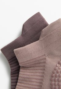 Dva para čarapa s teksturom u nijansama mauve i svijetlopurple, s rebrastim uzorcima i glatkim detaljima.