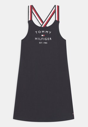Abito senza maniche blu navy con spalline incrociate a righe rosse, bianche e nere, testo "Tommy Hilfiger Est. 1985" e logo sul davanti.