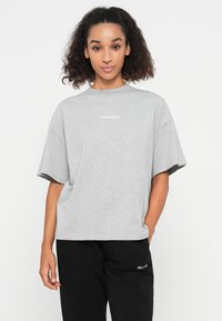 Gray oversized t-shirt made of cotton blend. Features short sleeves and a crew neckline with a small white logo at the front.