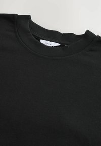 Black crew neck t-shirt made of soft cotton. Features a smooth texture and subtle stitching. Label visible inside neckline.