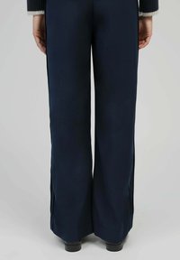 Pantalons à jambes larges bleu marine en tissu lisse, présentant un design épuré avec des ourlets fendus et sans matériel ou embellissements visibles.