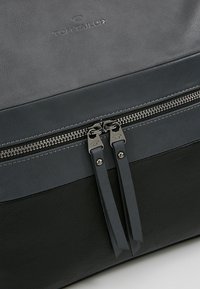 Bolso de cuero negro con una textura suave, acentos en gris oscuro, cierre con cremallera y herrajes en plata con detalle del logotipo.