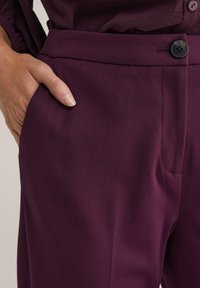 Burgundské kalhoty vyrobené z hladkého materiálu, s rovným střihem, bočními kapsami a jedním knoflíkem na pásku.
