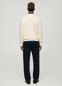 Felpa chiara con colletto navy, abbinata a pantaloni blu scuro, vista da dietro. Tessuto liscio, design minimalista.