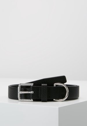 Ceinture en cuir noir texturé avec boucle rectangulaire argentée et anneau en D, placée enroulée sur une surface blanche sur un fond gris uni.