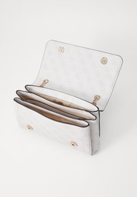 Hvid mønstret tegnebog med tre rum, tekstureret stof, guld hardwaredetaljer og tryklås. Indvendigt har den en beige foring.