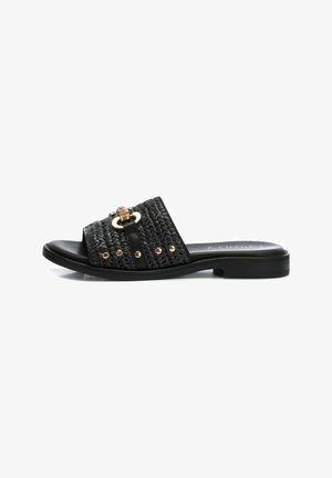 Sandal de slide negro con parte superior trenzada, acentos de hardware dorado, diseño de punta abierta y suela plana. Presenta tachuelas decorativas a lo largo de la correa.