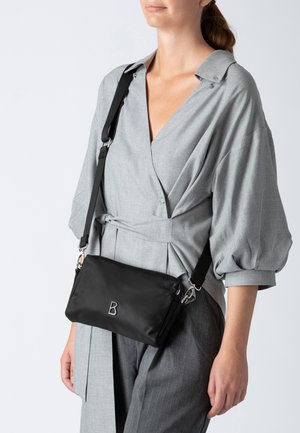 Borsa a tracolla nera in nylon con una forma rettangolare elegante, caratterizzata da un logo argento "B" e un tracollo regolabile con accessori in metallo.