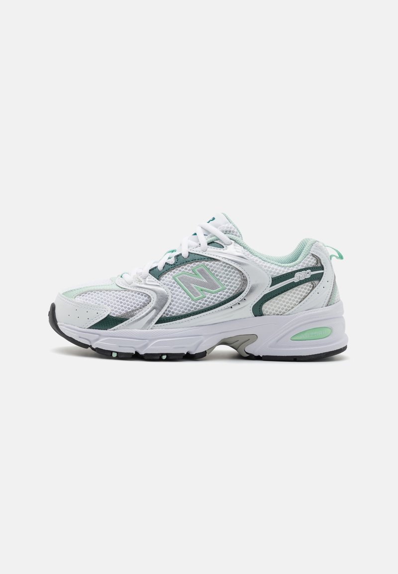 Chaussure de sport New Balance blanche et verte en tissu mesh, à lacets et semelle coussinée, vue de profil sur fond blanc.