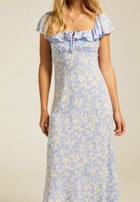 Pitkä, vaaleansininen mekko, jossa on pieniä keltaisia kukkakuoseja. Yksityiskohtina rypytetyt lyhyet hihat ja nauhakiinnitys kaula-aukossa. Silkkinen pinta.